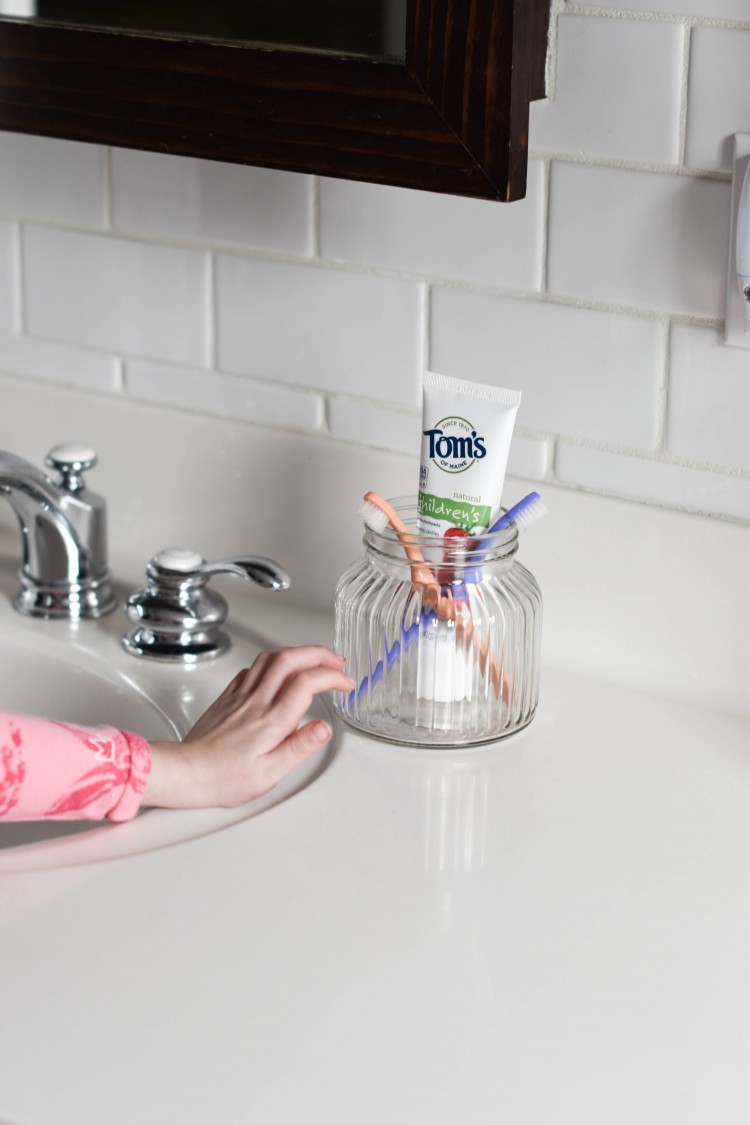 cutest toothbrush and toothpaste storage idea - store them in a glass jar on the counter so kids can reach